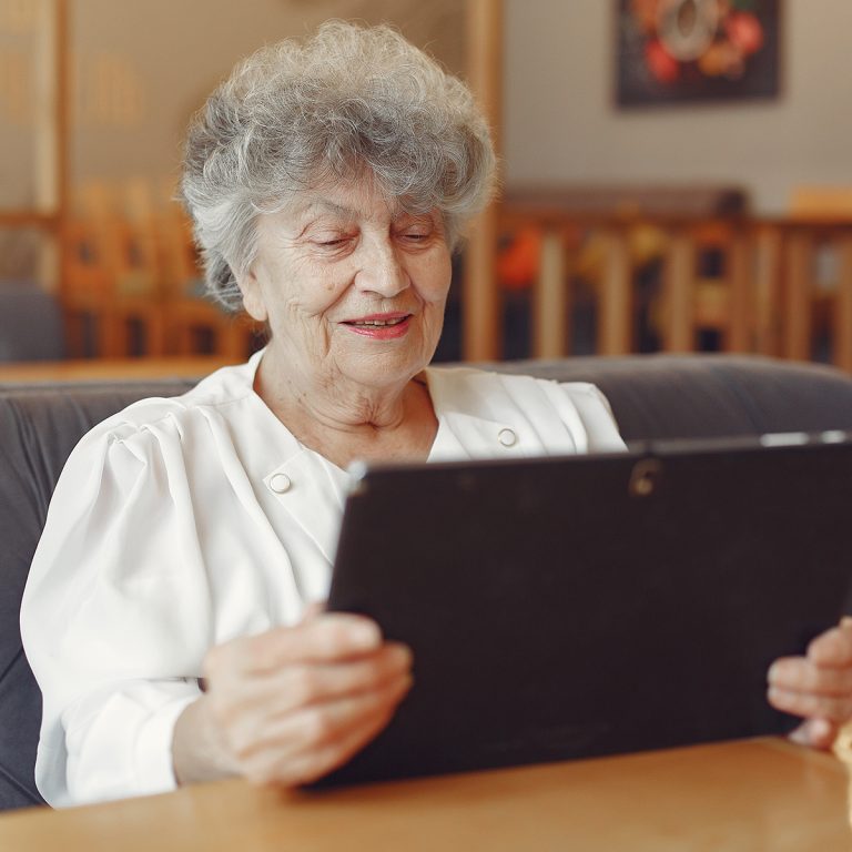 Elegant old woman sitting in a cafe and using a laptop