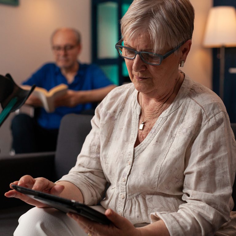 Senior person with crutches looking at modern tablet