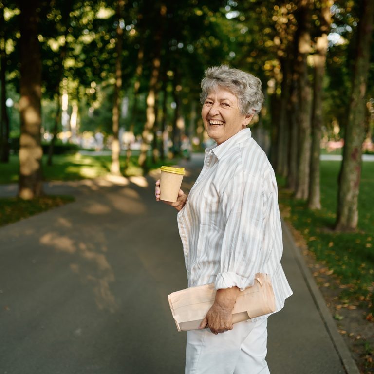Funny granny drinks coffee in summer park